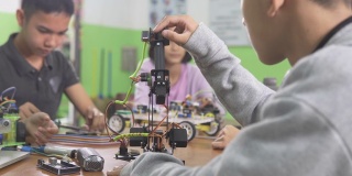 教育主题:聪明的学校男孩建立一个小机器人手臂和使用笔记本电脑编程软件的机器人工程类作为学校科学项目。科学与人的观念。