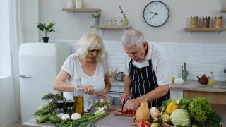 年长的素食主义者祖母和祖父在家用新鲜蔬菜做沙拉视频素材模板下载