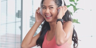 近距离的快乐年轻亚洲女人听音乐耳机和跳舞，而从家庭锻炼休息，4K分辨率，慢动作