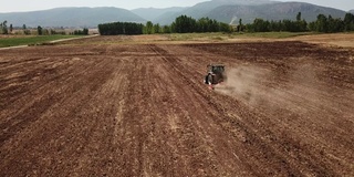 航拍拖拉机使用拖车播种机在农民的田地里播种机犁地