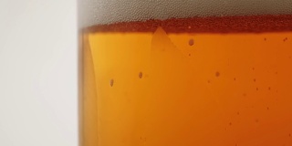 新鲜的啤酒。美味的精酿啤酒放在啤酒杯里，放在黑色背景的木桌上。冰凉的新鲜啤酒，带有水滴，泡沫和泡沫。关闭了。4 k