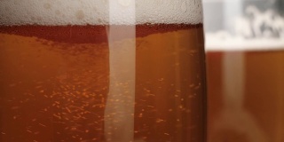 新鲜的啤酒。一杯清凉可口的啤酒放在一张木桌上，背景是开心果。冰凉的新鲜啤酒，带有水滴，泡沫和泡沫。微距镜头。4 k