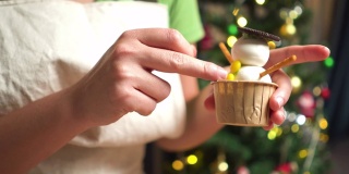 特写镜头:为冬天传统节日圣诞节准备烘焙糕点食品和甜点摊，在晚上在厨房里用้手工添加一个黄色按钮和黄色按钮形状的巧克力自制纸杯蛋糕做一个雪人