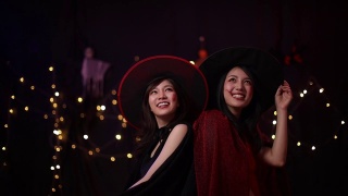 亚洲妇女穿着恶魔和女巫的服装在万圣节派对上玩得很开心。视频素材模板下载