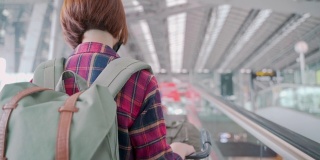 后视图在机场自动扶梯上佩戴防护口罩的亚洲女性游客