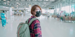 在新冠肺炎期间，亚洲女性游客佩戴防护口罩在机场保护冠状病毒