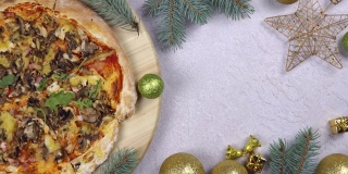 平铺的披萨在木托盘上360度旋转，围绕圣诞装饰。