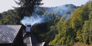 在山景背景下，浓烟从烟囱升起。村老房子。农村的场景。郊区的村庄。山间小屋烟囱在秋天的早晨