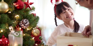 快乐的亚洲女孩和她的祖父几世同堂装饰圣诞树一起准备快乐的节日冬天。