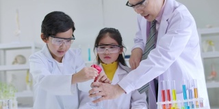 小学科学课堂:亚洲儿童在科学实验室实验台上统一学习各种颜色的试管玻璃水。