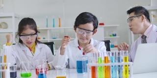 小学科学课堂:亚洲儿童在科学实验室实验台上统一学习各种颜色的试管玻璃水。