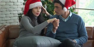 一对可爱的夫妇在沙发上聊天庆祝圣诞节的慢镜头。