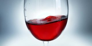 红酒在玻璃杯中像波浪一样从一边溅到另一边的创意宏慢动作视频。玻璃与溅起的葡萄酒近距离。