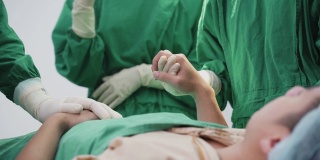 亚洲病人在手术室等待由外科医生和医疗队在医院手术室进行手术。医生通过握手和触摸病人的肩膀来给予病人鼓励