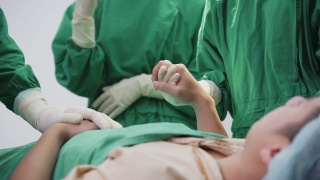 亚洲病人在手术室等待由外科医生和医疗队在医院手术室进行手术。医生通过握手和触摸病人的肩膀来给予病人鼓励视频素材模板下载