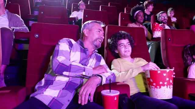 老人和他的孙子在电影院看电影