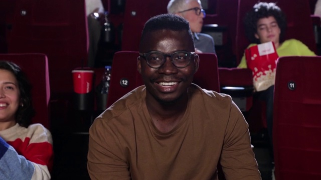 年轻的非裔美国人在电影院欣赏有趣的电影