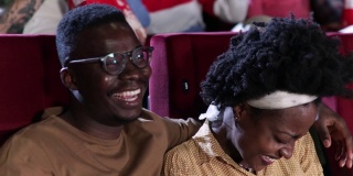 一对非洲裔美国夫妇在看喜剧电影，在电影院玩得很开心