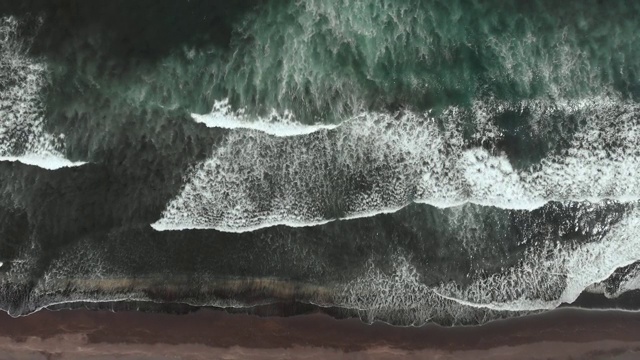 戏剧性的景象——巨大的黑色海浪撞击着沙滩