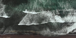 戏剧性的景象——巨大的黑色海浪撞击着沙滩