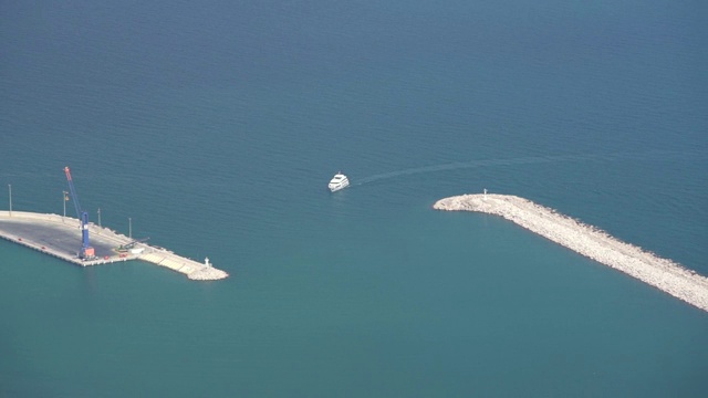 在一个阳光明媚的日子，客轮沿着蔚蓝海湾驶往港口