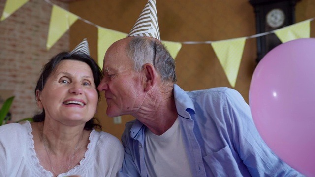 虚拟关系，戴着帽子的爷爷和奶奶在笔记本电脑的摄像头上聊天，在社交距离中庆祝在线派对和生日快乐，因为冠状病毒和大流行坐在家里的照片上，看着摄像头