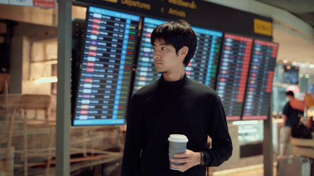 亚洲游客拿着咖啡杯站在机场候机厅