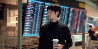 亚洲游客拿着咖啡杯站在机场候机厅