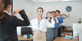 早上，亚洲商务女性领导商务人员在办公室进行几分钟严格的弯曲、伸展和推挤运动，这是常规健美操练习的一部分。