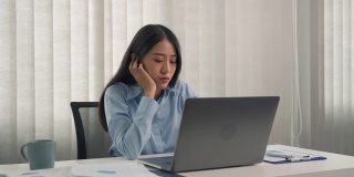 年轻的亚洲女性对工作感到厌烦，觉得在下午处理笔记本电脑上的数据很懒。