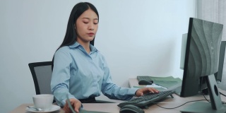 亚洲女性软件开发人员坐在电脑前看屏幕上的计算机代码。