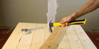 用锤子把钉子钉进木板。一名建筑工人以慢动作抛出并抓住锤子。木匠提高了使用工具的技术。锤子在空中翻滚。