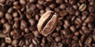 超慢镜头微距拍摄飞行的咖啡豆对旋转的背景新鲜烘焙的咖啡。
