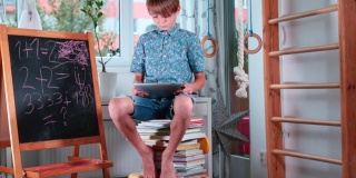 十几岁的男孩坐着看书，手里拿着平板电脑。互联网将取代成堆的书。