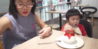 亚洲小男孩和妈妈在冰淇淋店吃冰淇淋