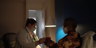 医生在老年妇女病人家中与她交谈-使用口罩