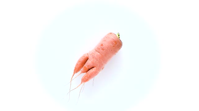 丑陋的胡萝卜在白色背景上旋转。有趣的，不正常的蔬菜或食物浪费概念。水平方向