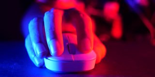 特写的网络运动玩家玩游戏和点击鼠标与彩色霓虹灯。