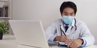 亚洲医生戴口罩在办公室写病人检查报告