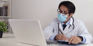 亚洲医生戴上眼镜和面罩，通过视频电话检查患者