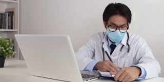 亚洲医生戴眼镜和口罩在办公室写病人检查报告