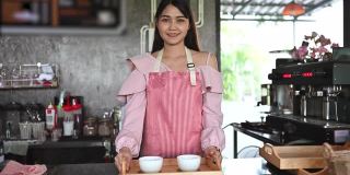 亚洲女咖啡师为顾客提供咖啡。创业的概念