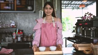 亚洲女咖啡师为顾客提供咖啡。创业的概念视频素材模板下载