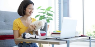 一个女孩正在客厅里和一只马耳他狗一起使用笔记本电脑。