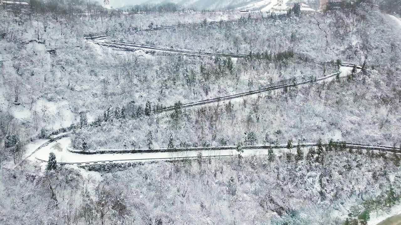 鸟瞰图弯曲的山路上山穿过松树和其他树木覆盖在冬天的雪。山在四川西岭。