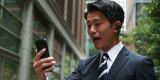 快乐的亚洲商人使用无线耳机进行电话会议