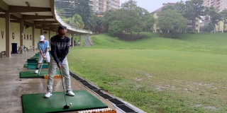 亚洲华人活跃的高级男子高尔夫球手在高尔夫练习场开球和挥杆他的潜水高尔夫球杆