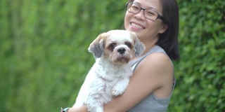 亚洲妇女拥抱她的狗在户外在家里