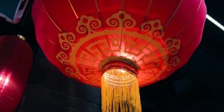 从屋顶上悬挂在老建筑边缘的传统红色球形中国灯笼，黄色的灯光从里面照亮四周。为国庆做准备。
