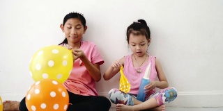 亚洲女孩一起在家里的地板上抽气球，为家庭装饰概念做准备。